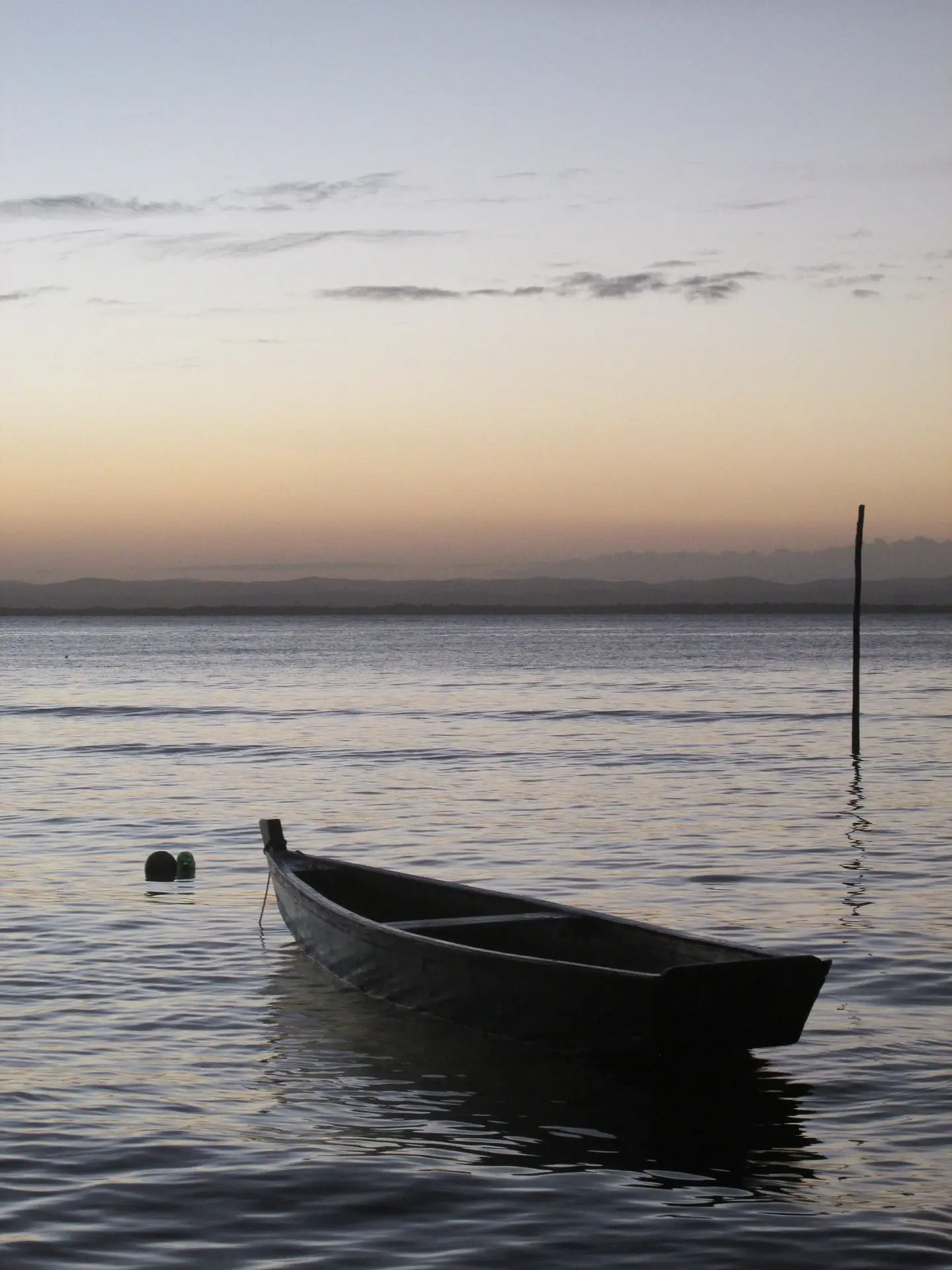 imagen de una barca en el mar con una puesta de sol en el horizonte