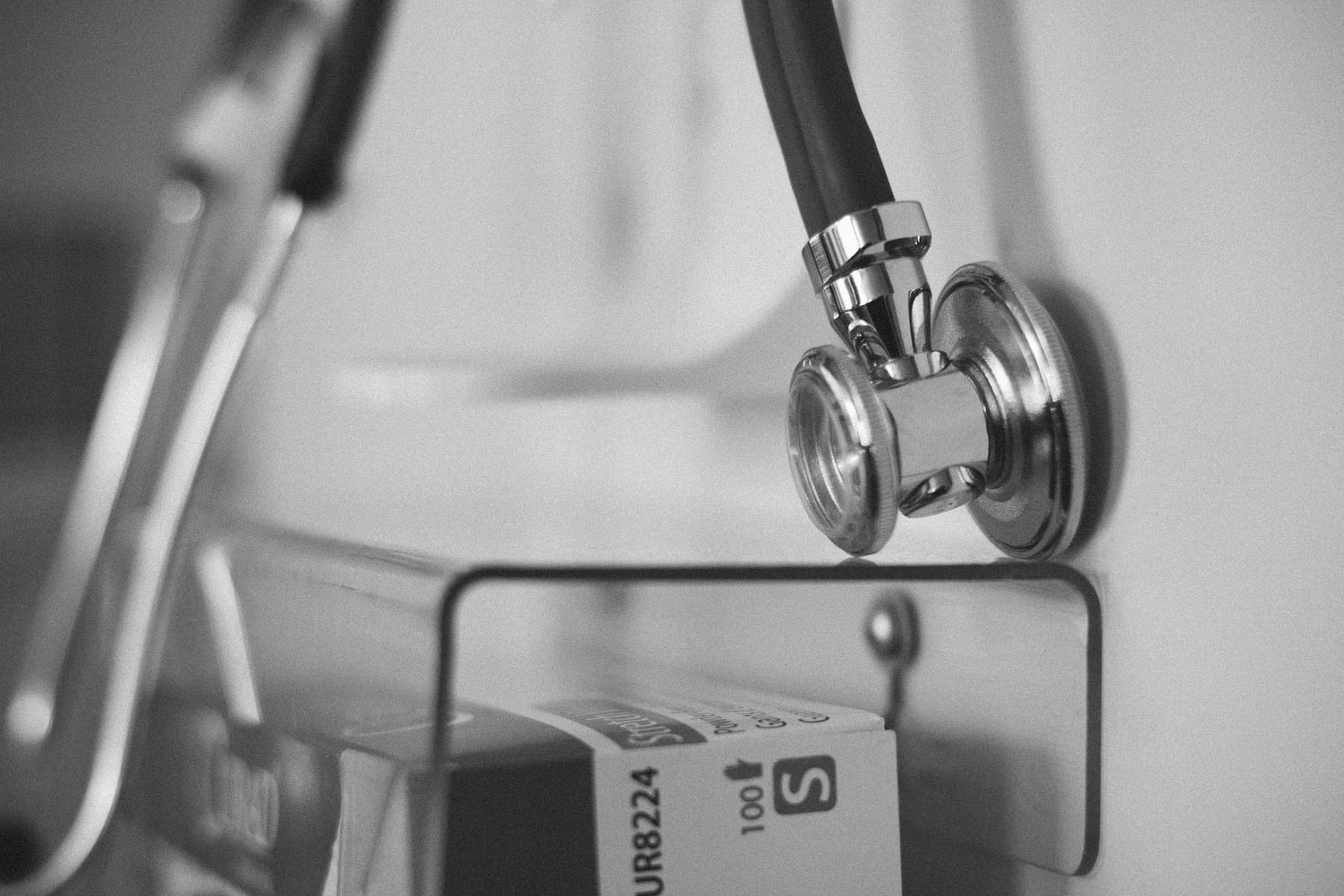 imagen en blanco y negro de un estetoscopio sobre caja transparente de medicinas