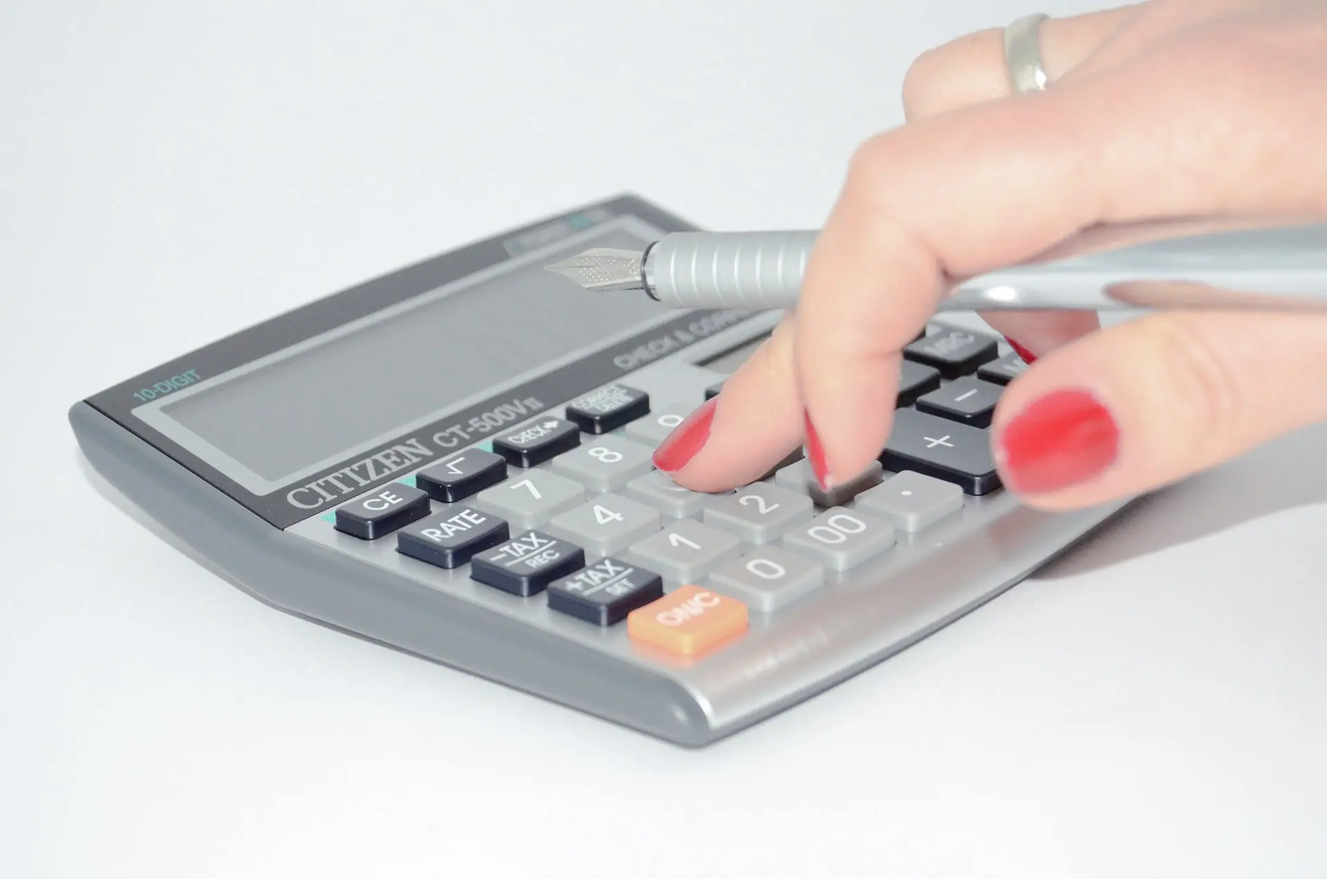 imagen de una mano tecleando en una calculadora sobre fondo blando